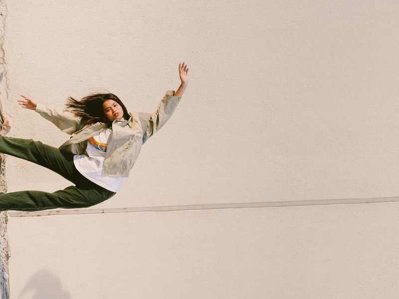 Person in a dynamic yoga flow pose against a minimal background.